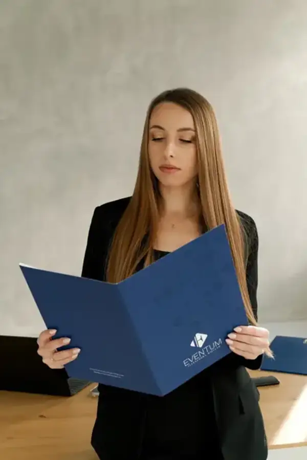 Księgowa czytająca dokumenty z teczki z logotypem firmy Eventum